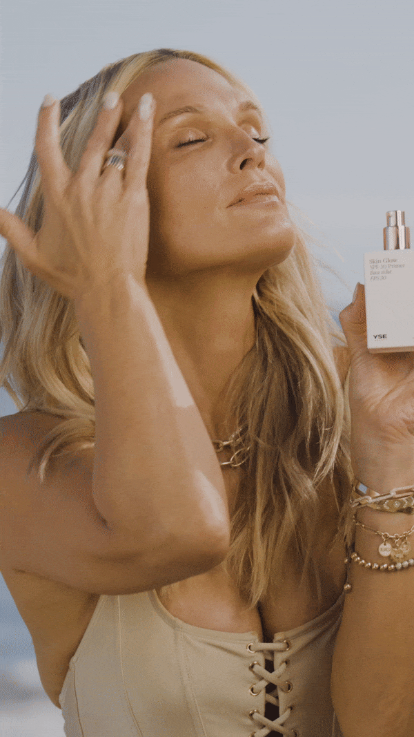 Woman applying Skin Glow SPF 30 Primer outdoors at the beach
